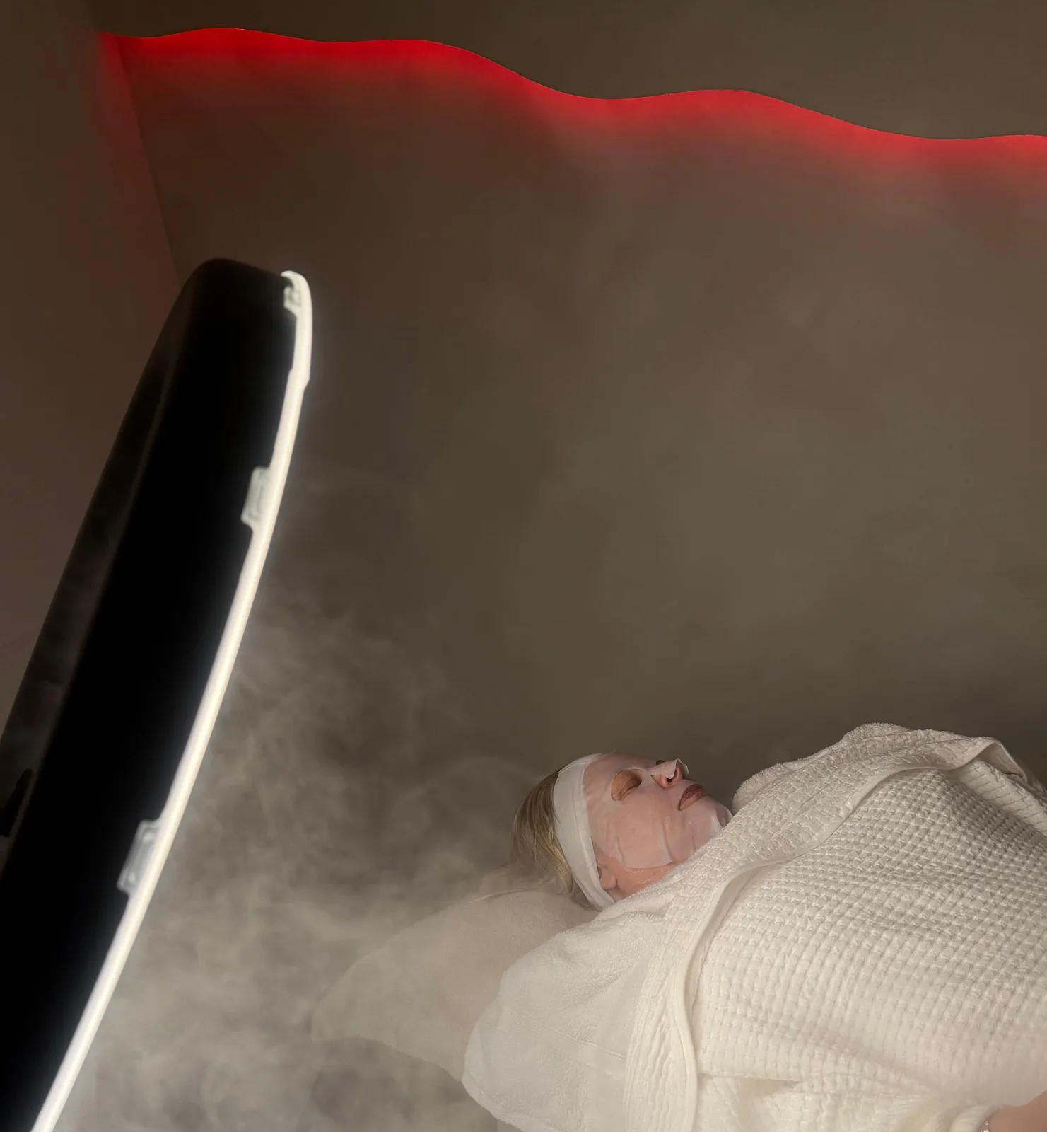 A client with a hydrating mask during a facial in the treatment room