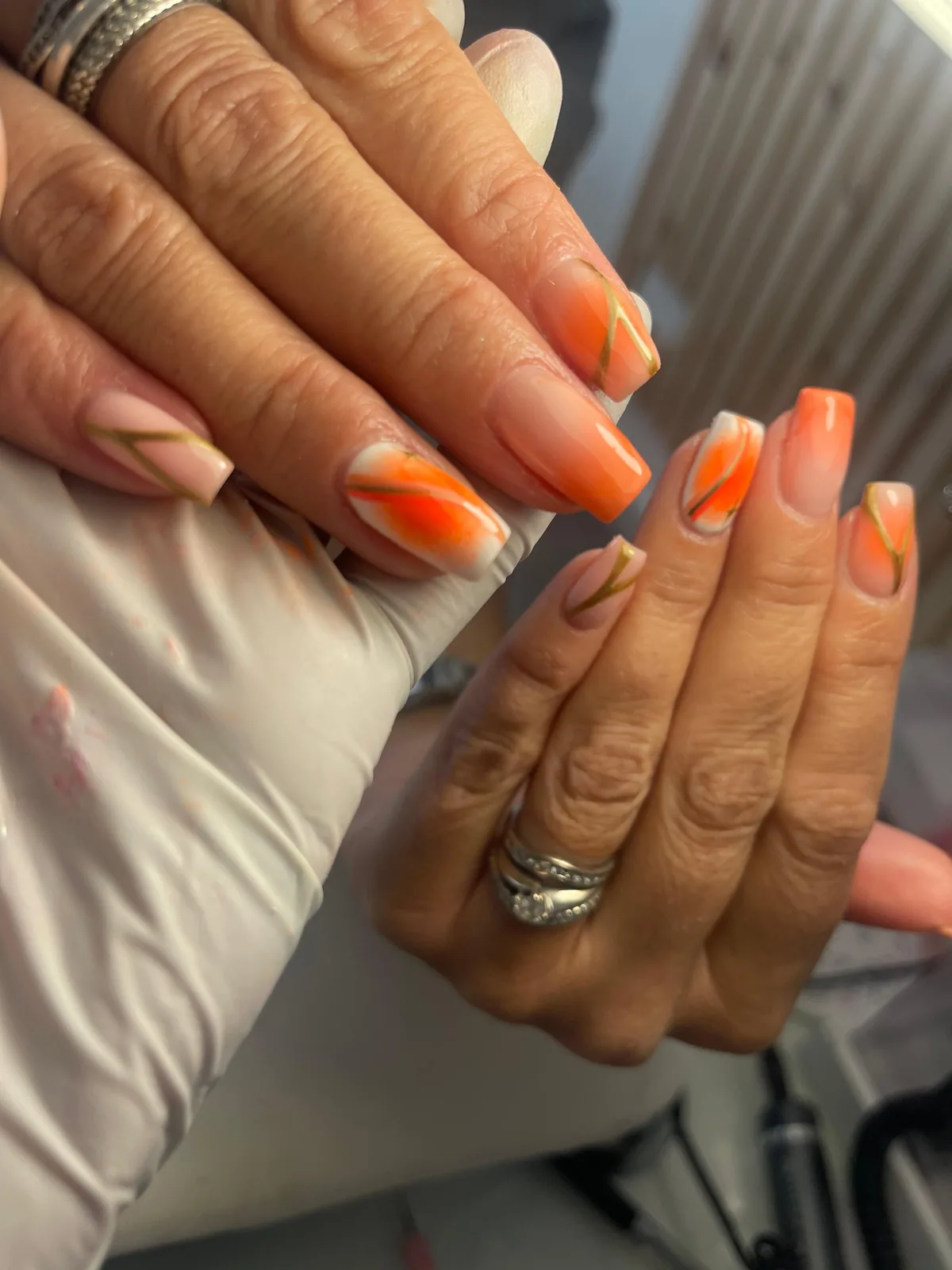 Square gloss nails with orange nail art, nude tones and gold detailing