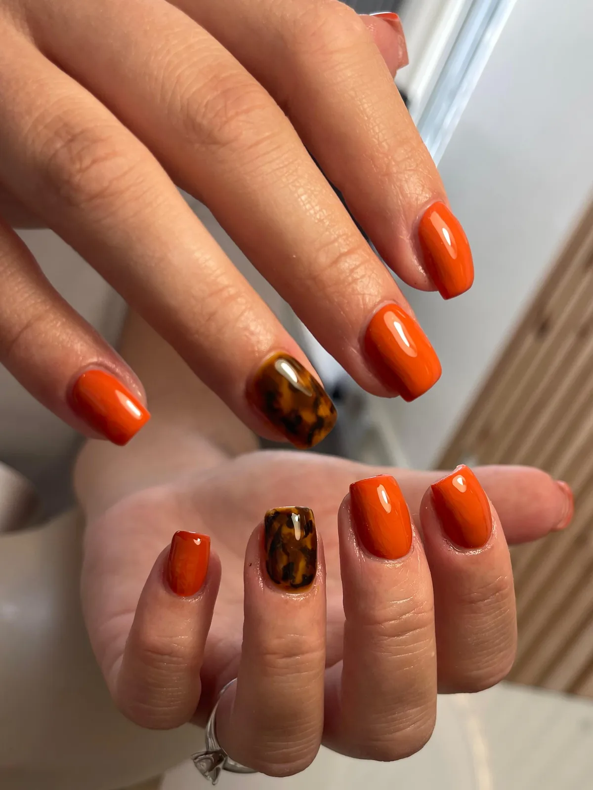 Short square BIAB nails in orange with tortoiseshell accent nails